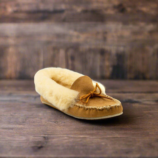 Brown moccasin slipper with fur lining on a wooden surface