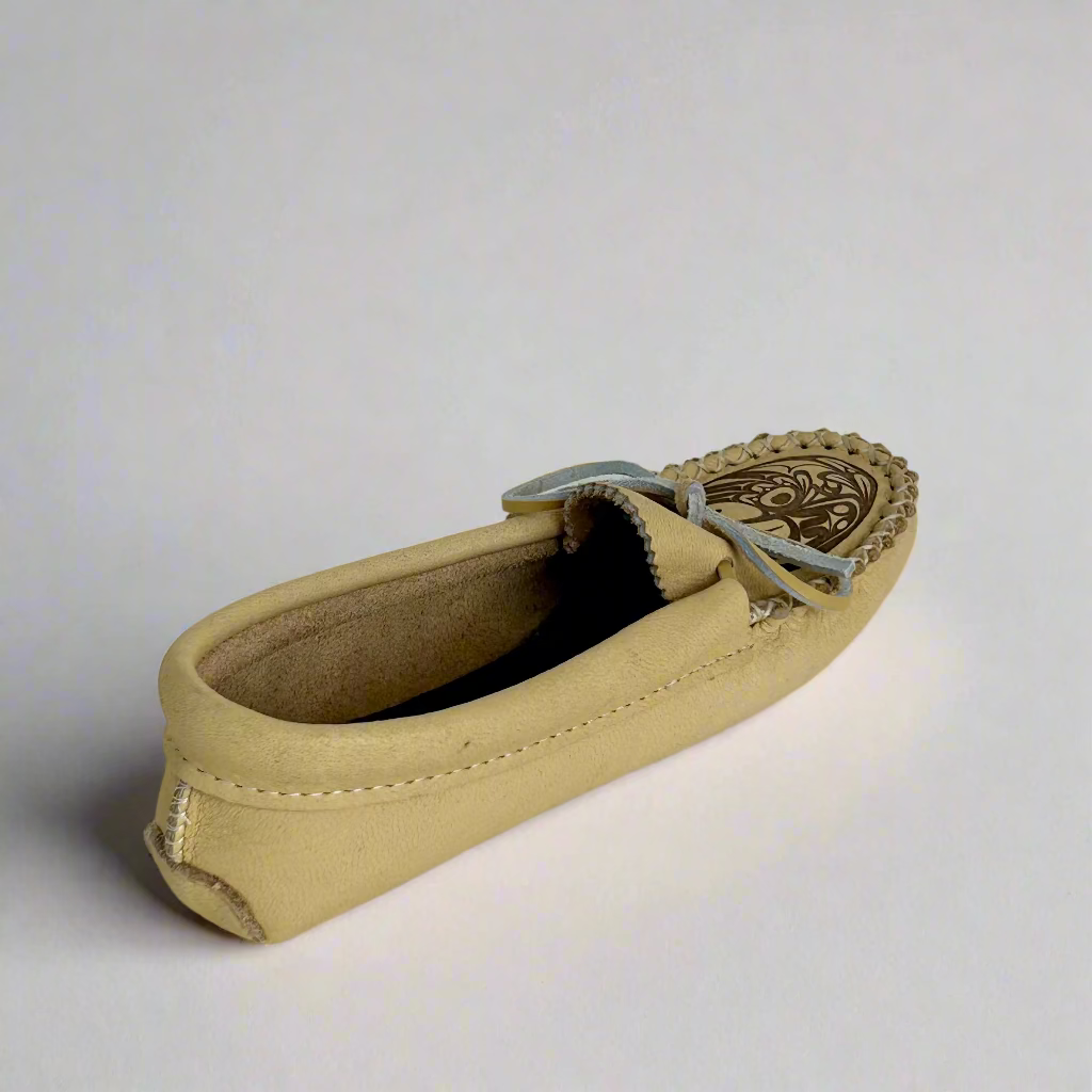 Beige loafer shoe with decorative sole on a white background