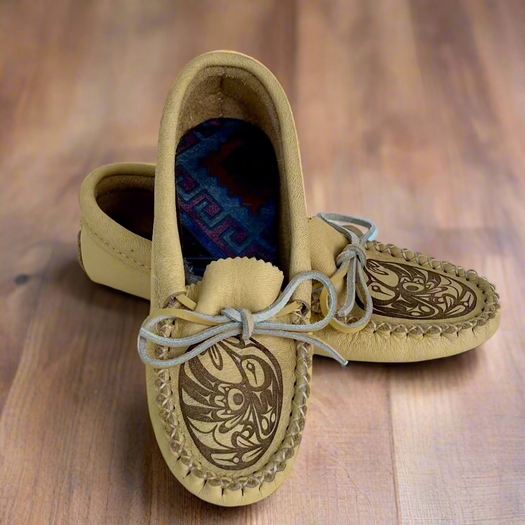 Pair of tan moccasins with intricate designs on a white background