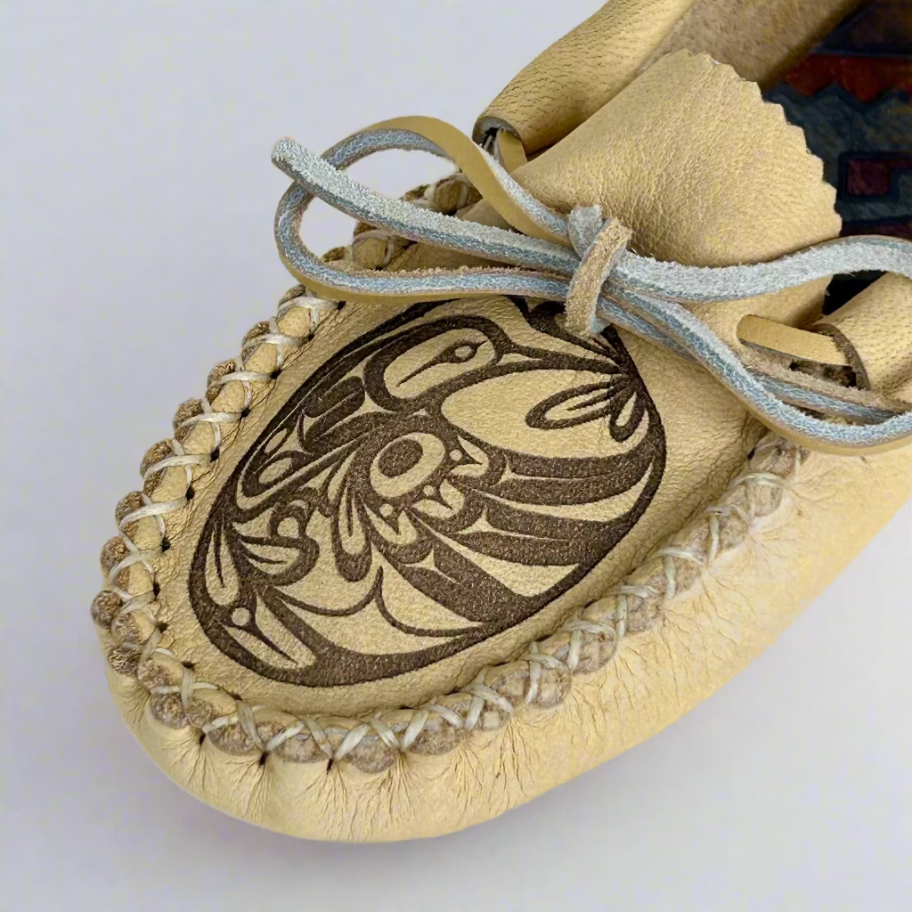 Beige moccasin with intricate black design on a white background