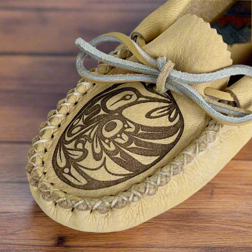 Beige moccasin with intricate black design on a white background