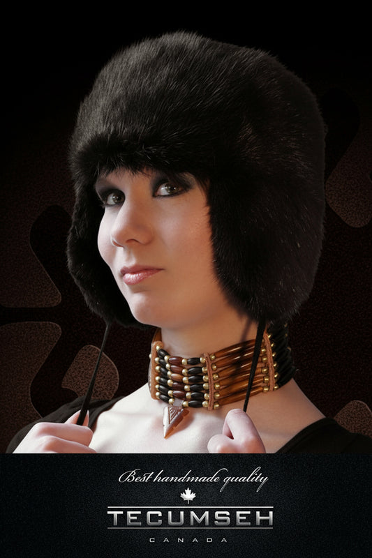 Woman wearing a black fur hat with 'Tecumseh Canada' branding on a dark background