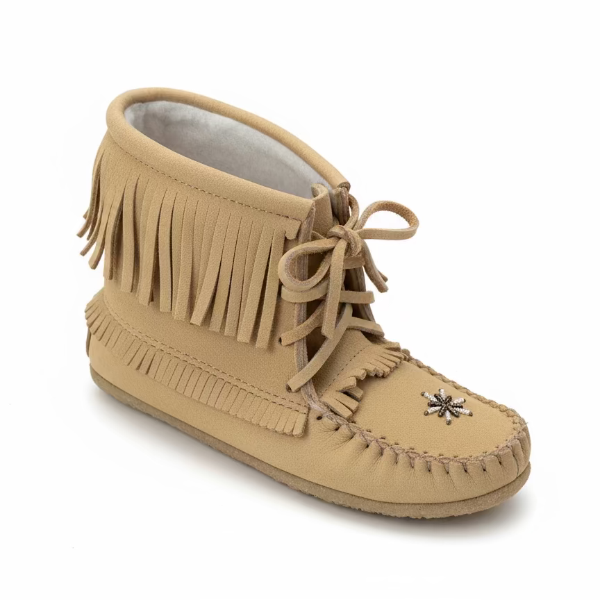 Beige moccasin shoe with fringes on a wooden floor