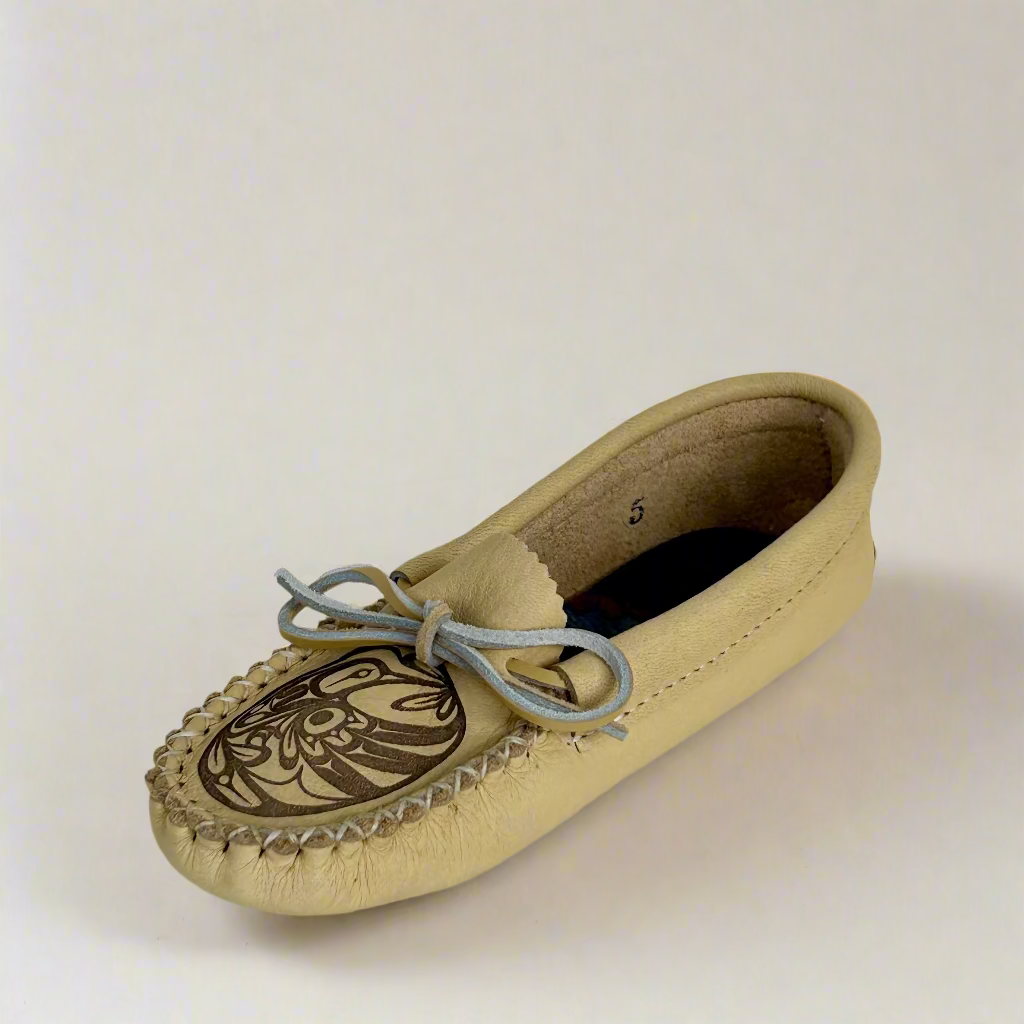 Beige moccasin shoe with a decorative design on a white background