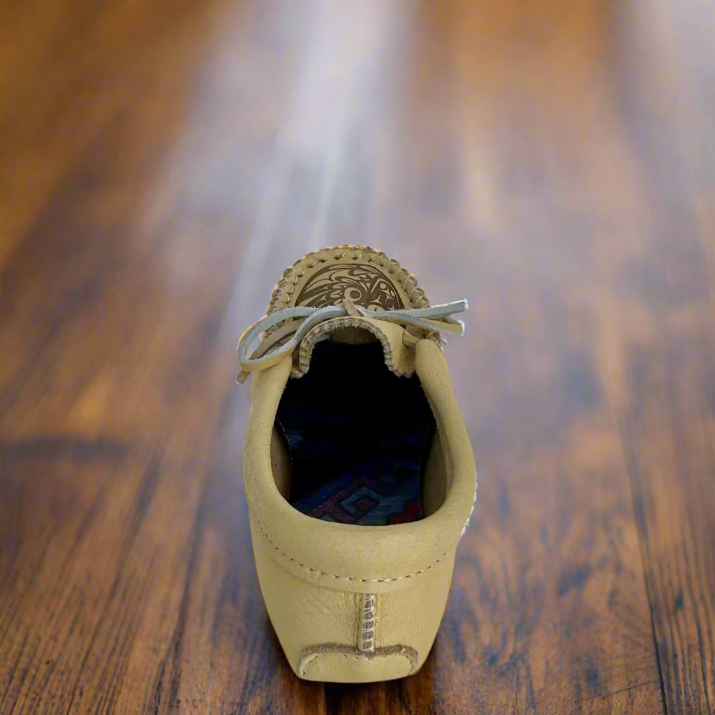 Beige leather shoe with decorative elements on a white background