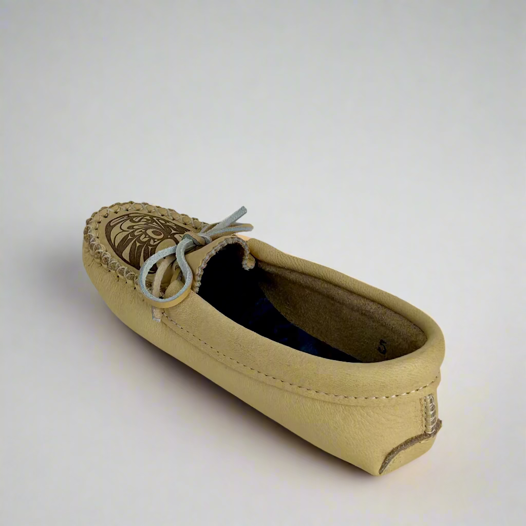 Beige moccasin shoe with decorative sole on a white background