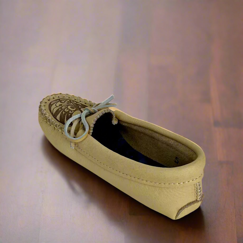 Beige moccasin shoe with decorative sole on a white background