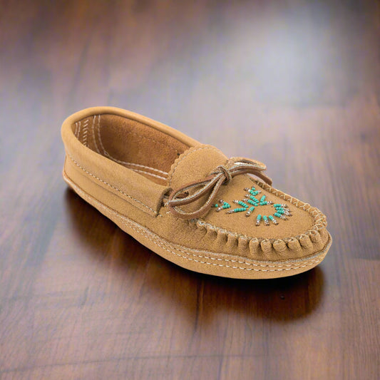 Tan moccasin shoe with turquoise bead design on a wooden surface