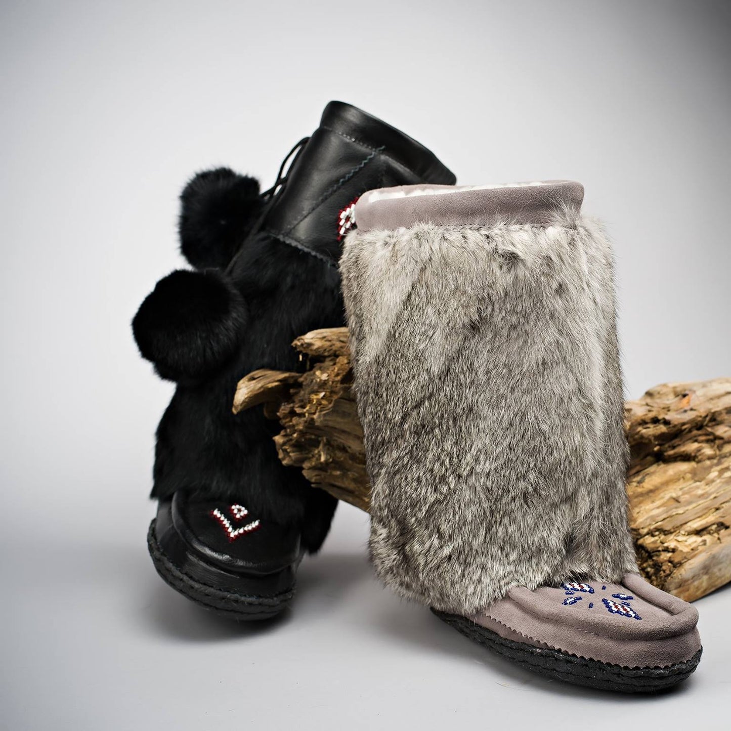 Pair of black boots with fur trim on a gray background