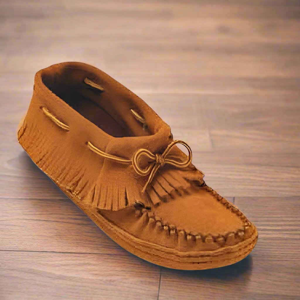 Brown moccasin shoe with fringes on a wooden floor
