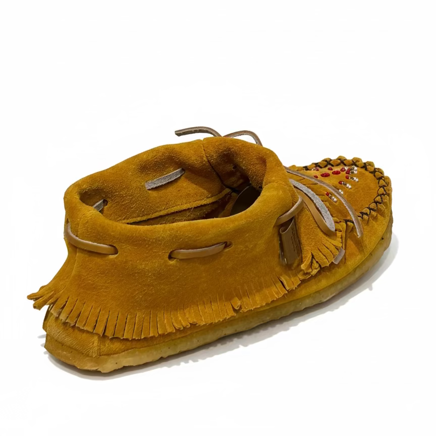 Yellow suede moccasin with fringes on a light gray background