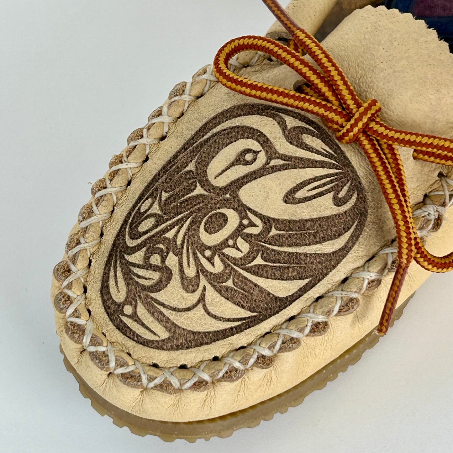 Beige moccasin with a decorative Hummingbird design on a white background