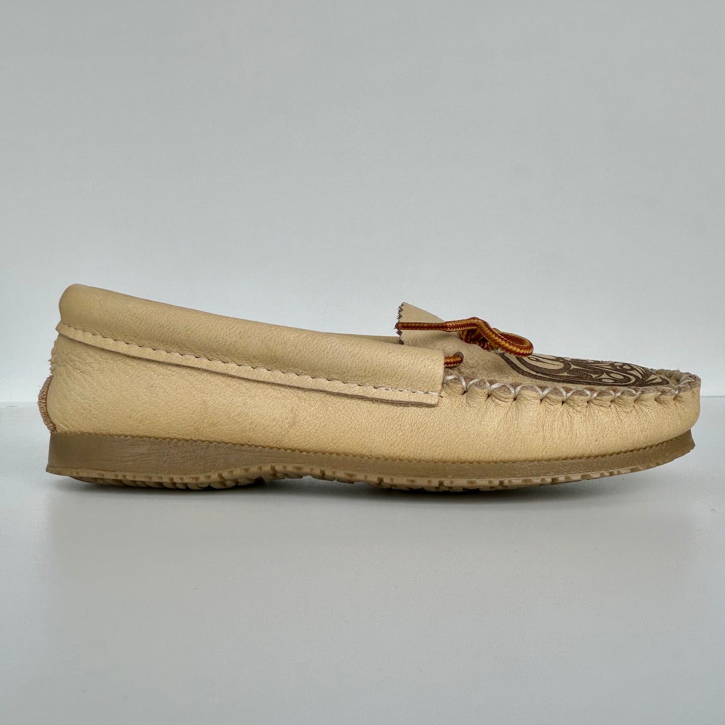 Beige moccasin shoe with brown accents on a light gray background