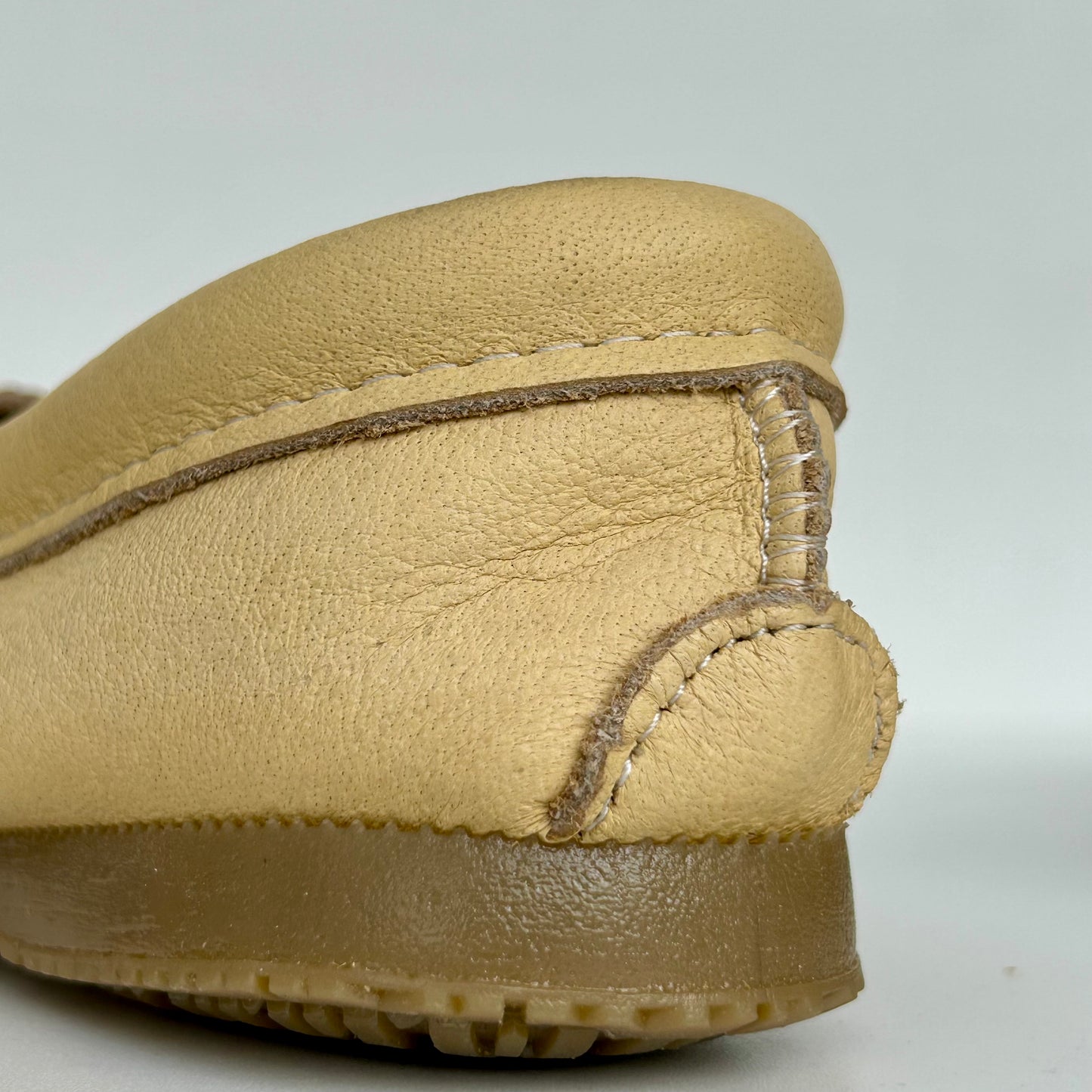 Close-up of a beige leather shoe on a light gray background