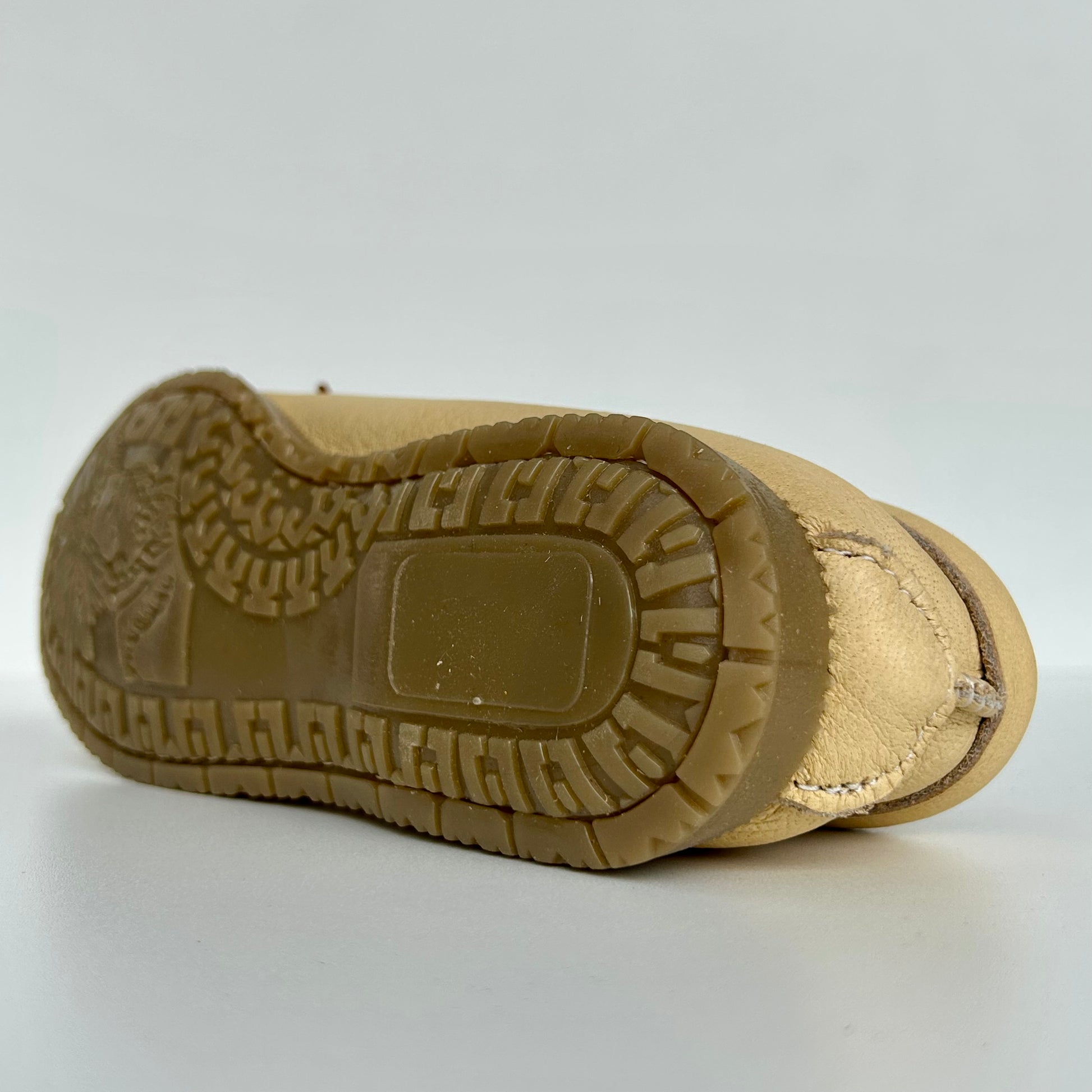 Close-up of a tan moccasin sole with tread pattern on a white background