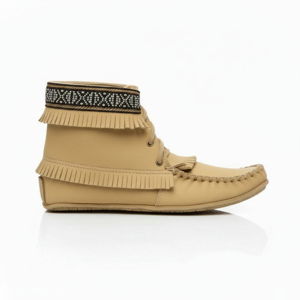 Tan moccasin boot with fringes and patterned band on a white background