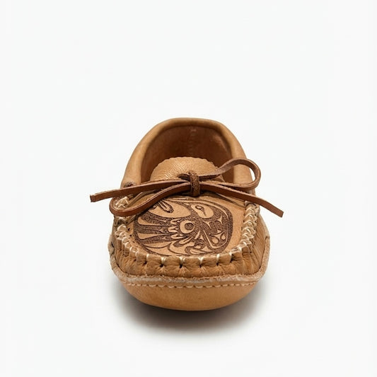 A single tan leather moccasin-style baby shoe with a decorative brown embroidered design on the toe and a matching brown bow on the upper, shown against a plain white background.
