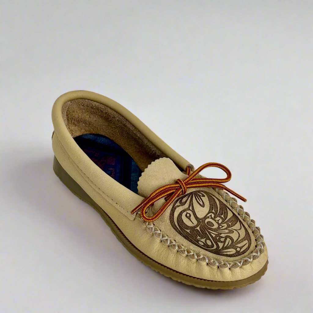 Beige moccasin shoe with brown sole and decorative pattern on a white background