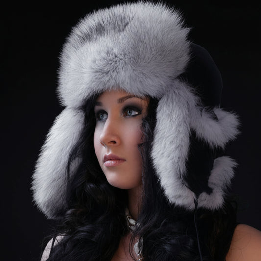 Woman wearing a gray fur hat with ear flaps against a dark background