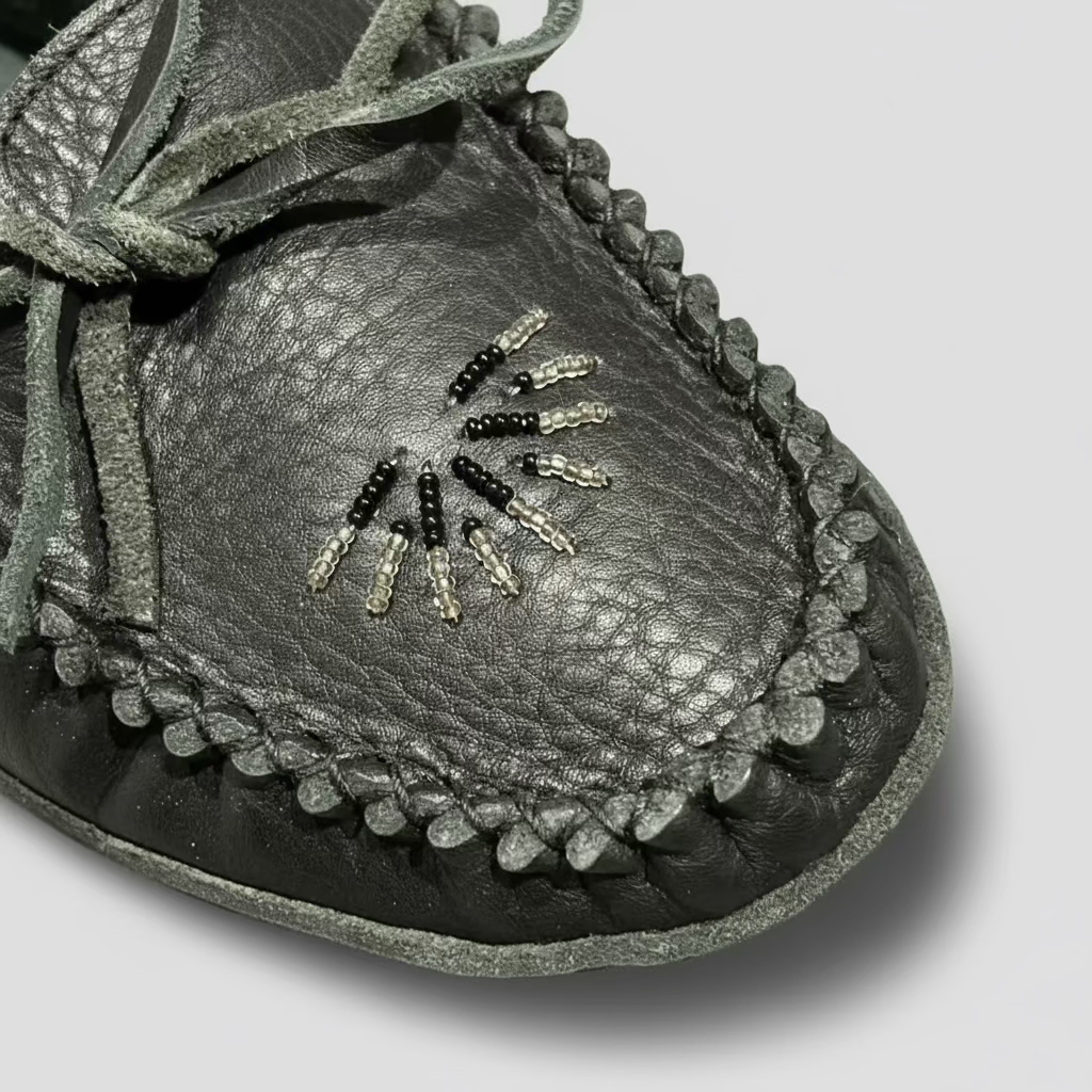 Black leather moccasin with beaded design on a wooden surface
