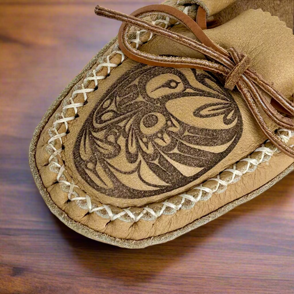 Leather moccasin with intricate design on a wooden surface