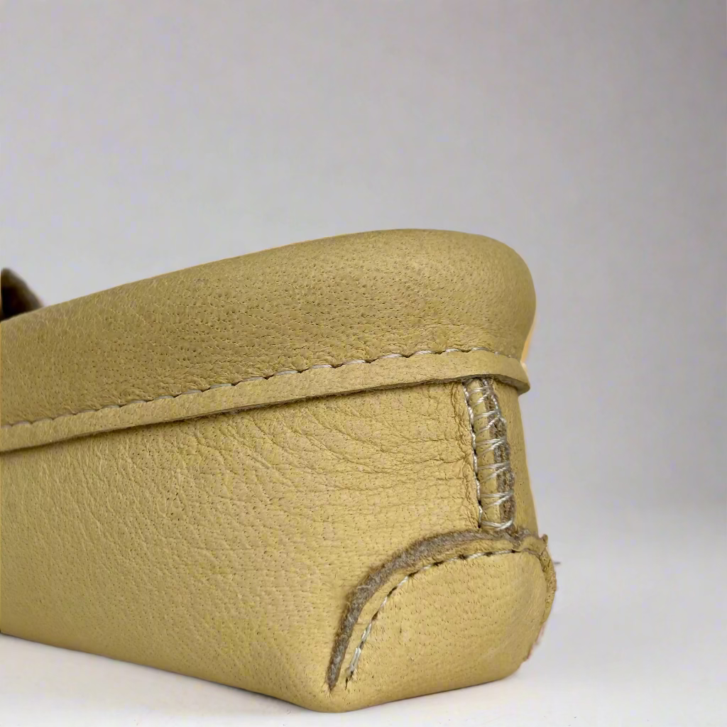 Beige leather moccasins with stitching detail on a gray background