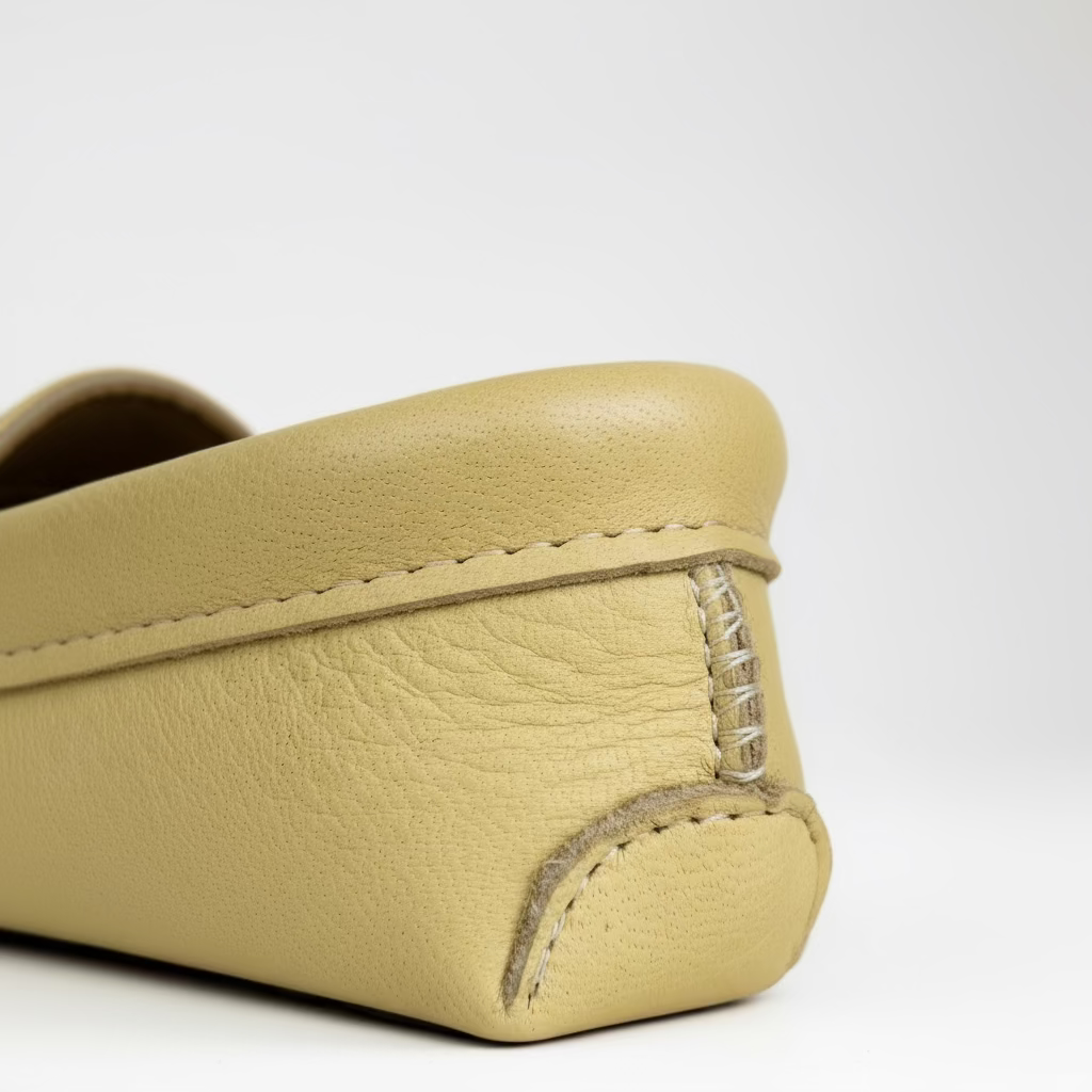 Beige leather moccasins with stitching detail on a gray background