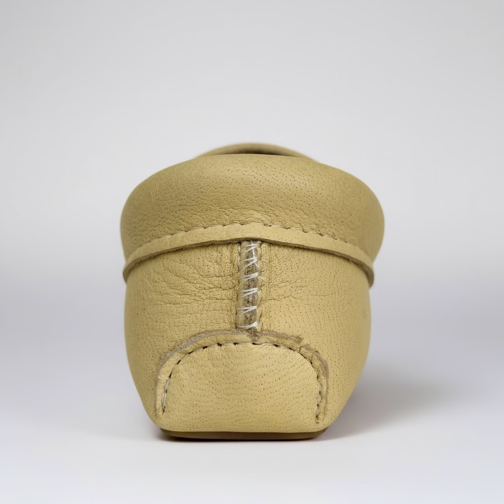 Beige leather shoe with stitching detail on a light gray background