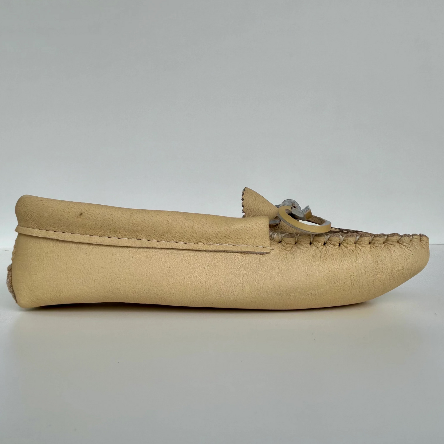 Beige moccasin shoe on a light gray background