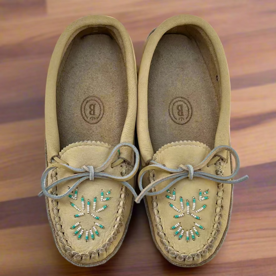 Pair of tan moccasin shoes with decorative elements on a wooden surface
