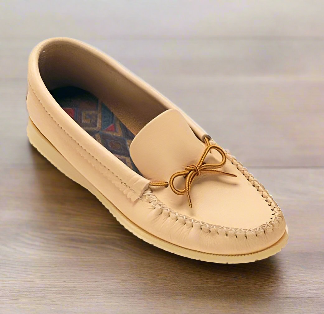 A beige men's moccasin with a double-padded insole and Indian rubber outsole, featuring a decorative bow on the top.