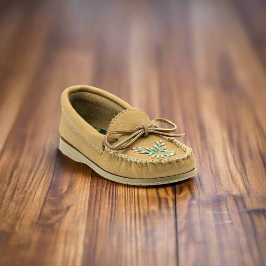 Tan slip-on shoe with decorative elements on a wooden surface