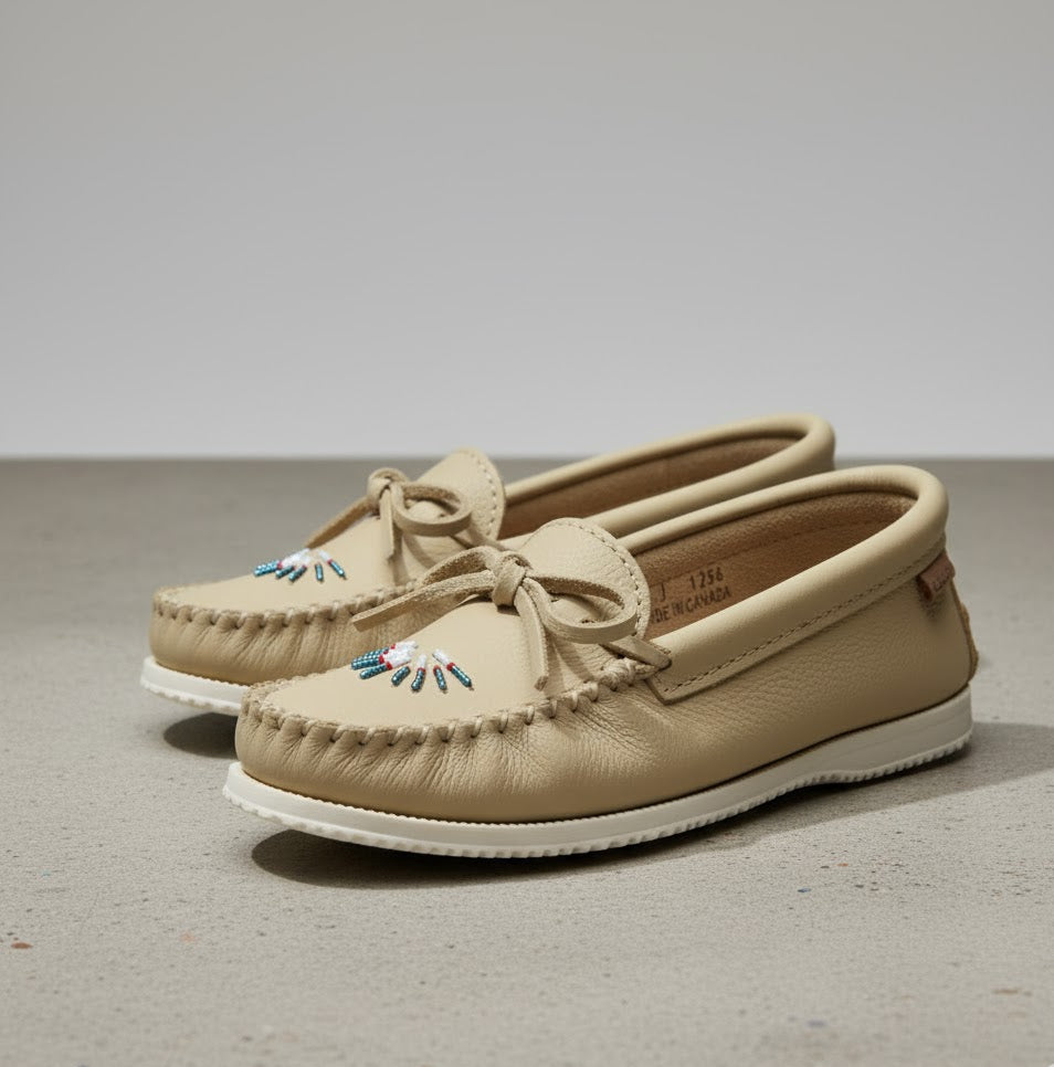 Pair of beige moccasin shoes with white soles on a neutral background