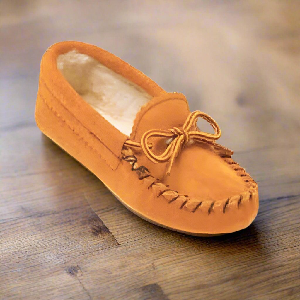 Orange moccasin slipper with bow on a wooden floor