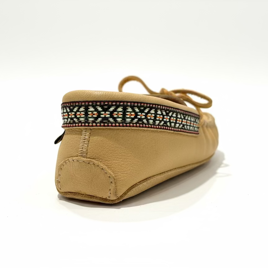 Tan slipper with decorative band on a white background