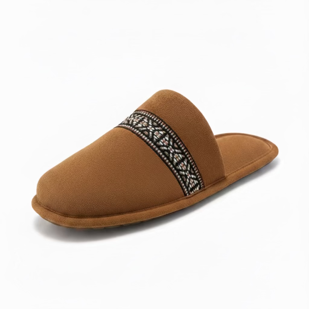 Brown slipper with decorative strap on a light surface