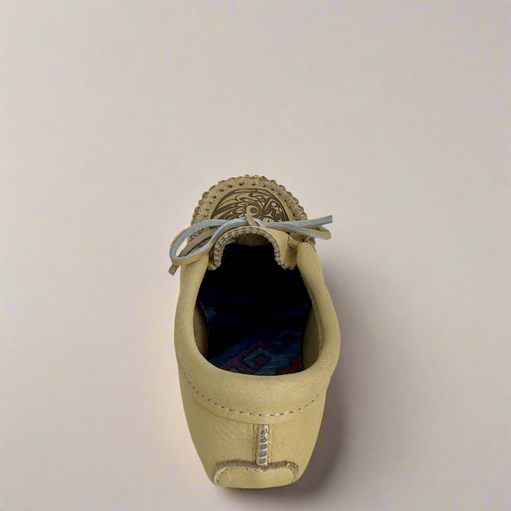 Beige leather shoe with decorative elements on a white background