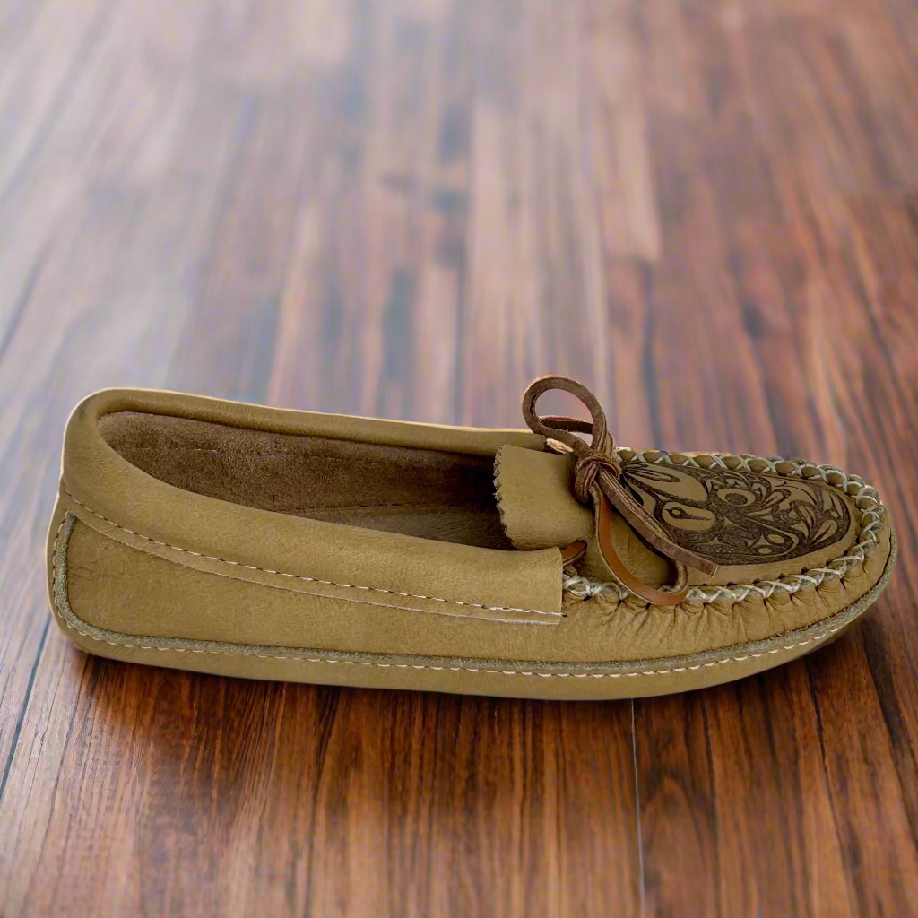 Brown slip-on shoe with decorative strap on a wooden surface