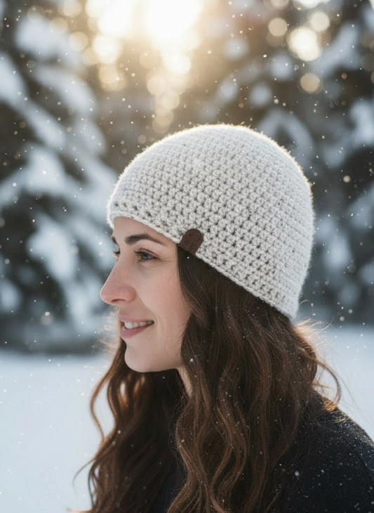 Woman wearing a white knit beanie in a snowy landscape
