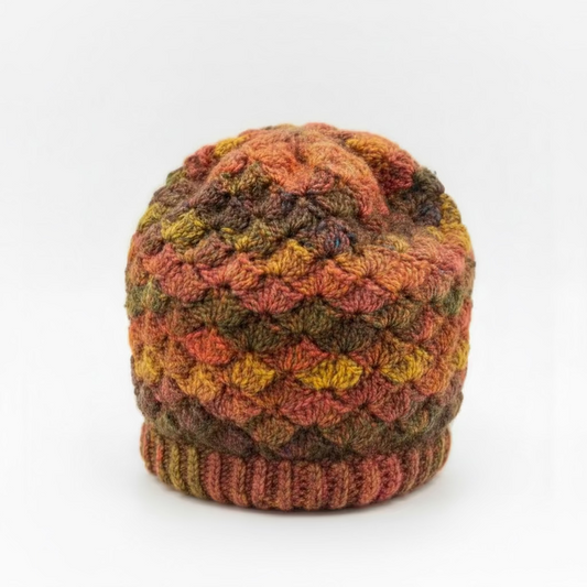 Multicolored knitted hat on a glass table with a blurred background