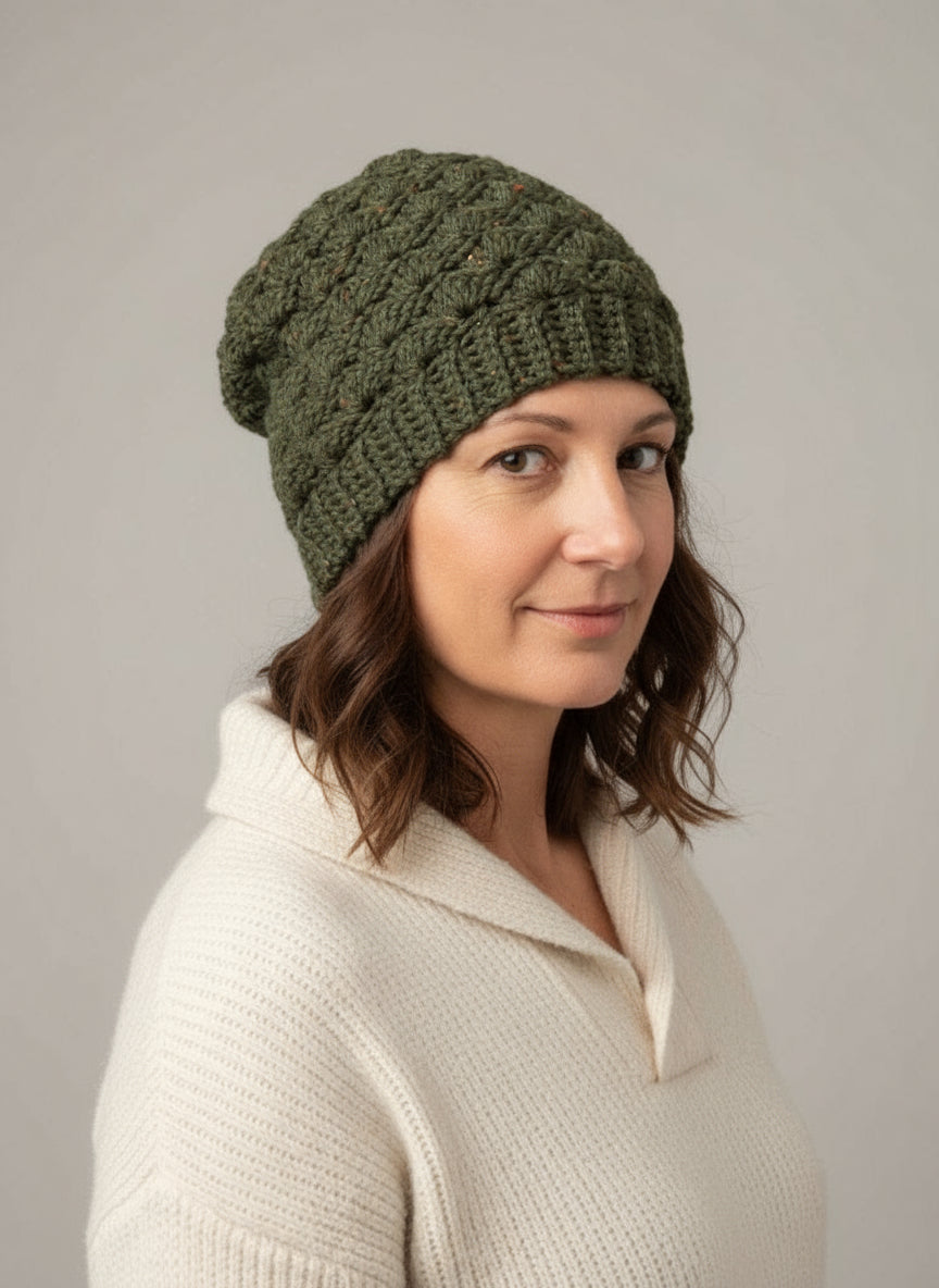 Woman wearing a green knitted beanie against a gray background