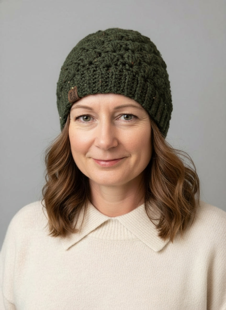 Woman wearing a green knitted beanie against a gray background