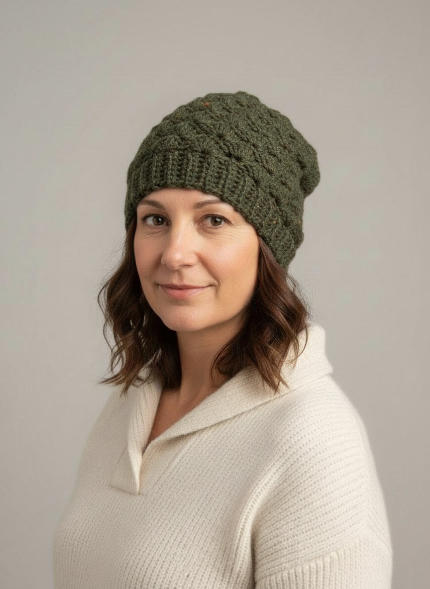 Woman wearing a green knitted beanie with a brand logo on a gray background