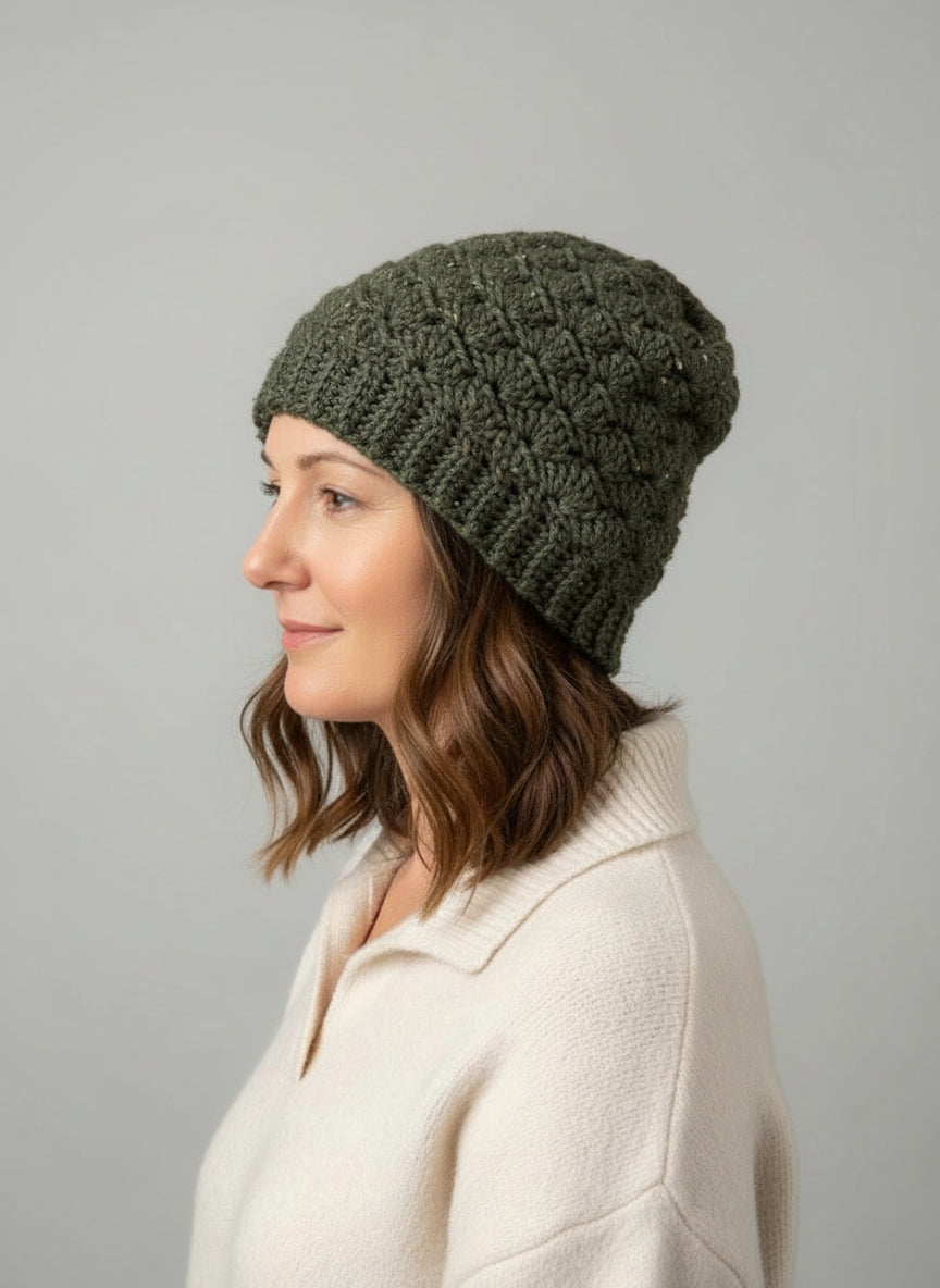 Woman wearing a green knitted beanie against a gray background