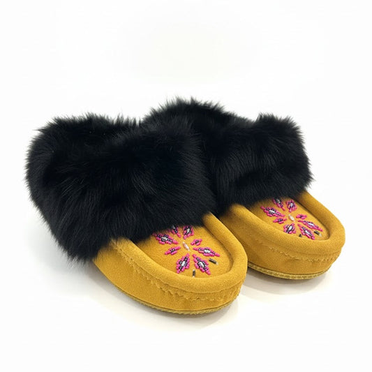 Pair of yellow slippers with black fur trim on a white background