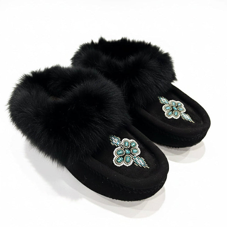 Black slippers with fur trim and decorative flowers on a white background