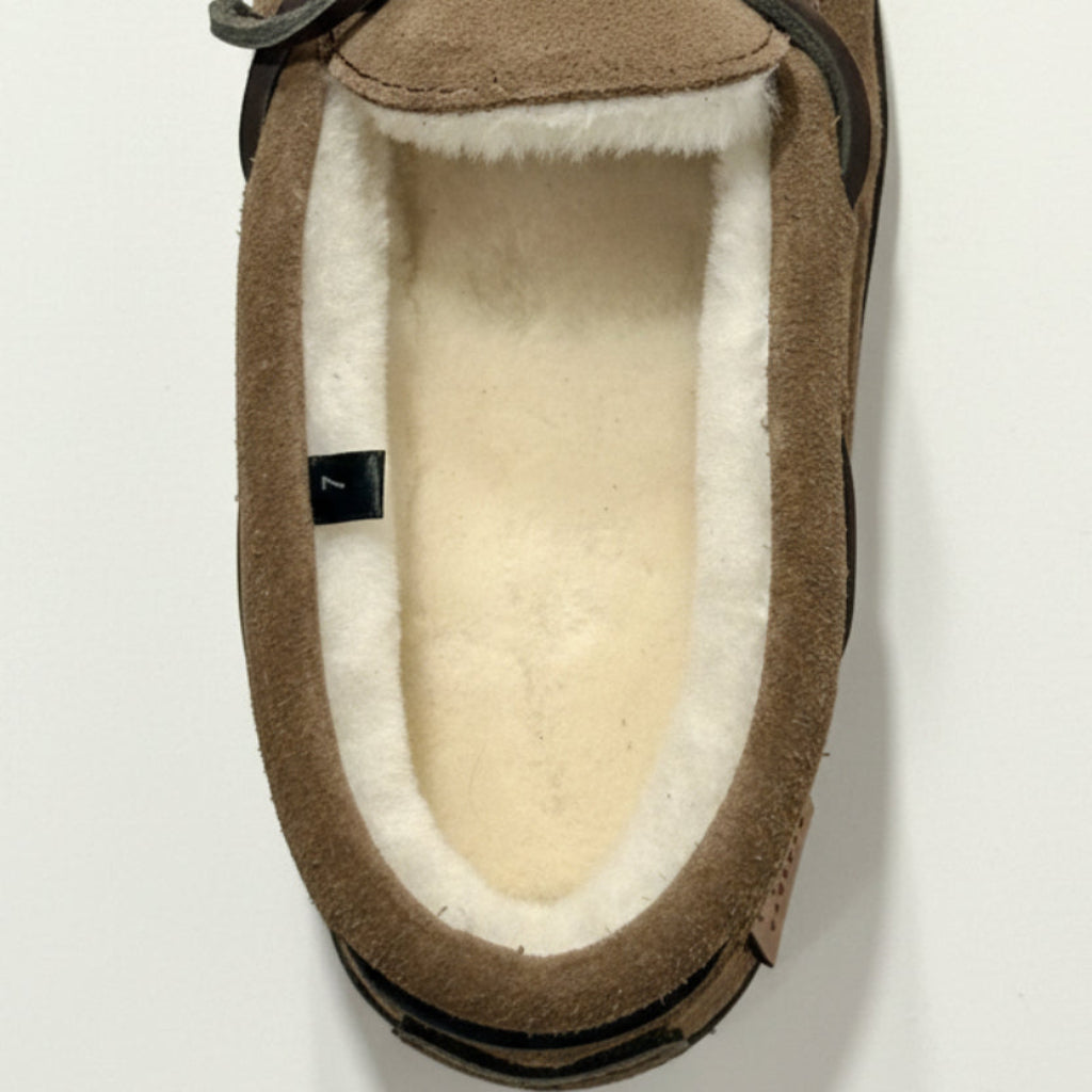 Brown slipper with white sheepskin interior lining on a light gray background