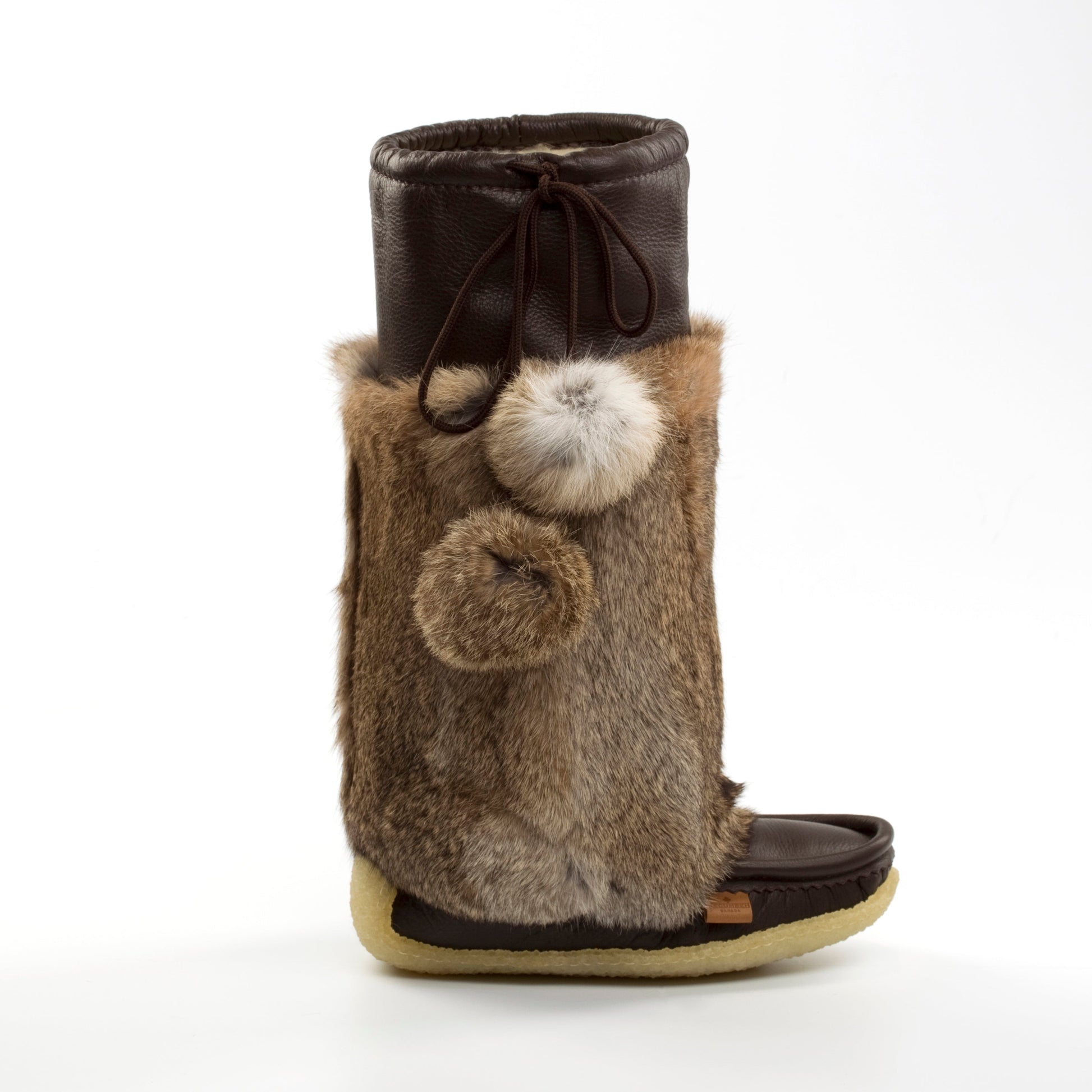 Brown boot with fur and pom-pom details on a white background
