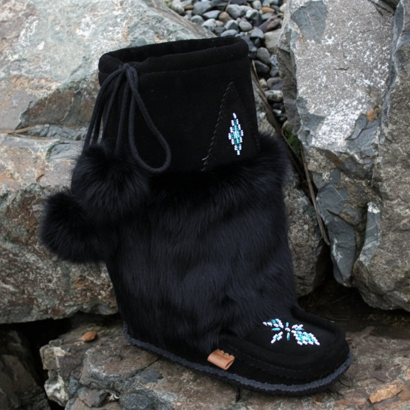 Black furry boot with decorative elements on a rocky surface