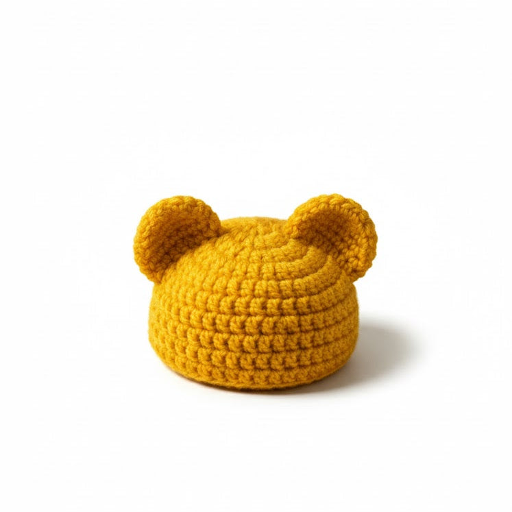 Yellow crocheted hat with bear ears on a white background